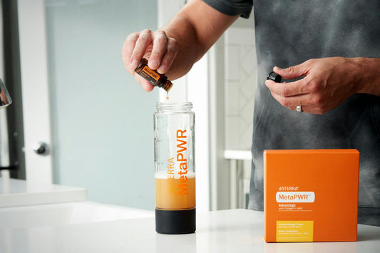 Маж подготвува MetaPWR напиток додавајќи етерично масло во шише со течен колаген, покрај пакување на производот на маса